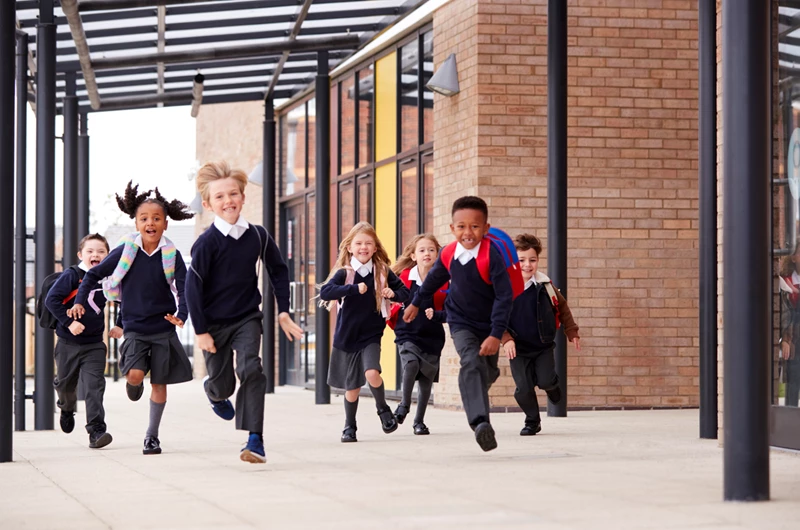 Several children sprinting playfully in front of a building, showcasing their energy and excitement.