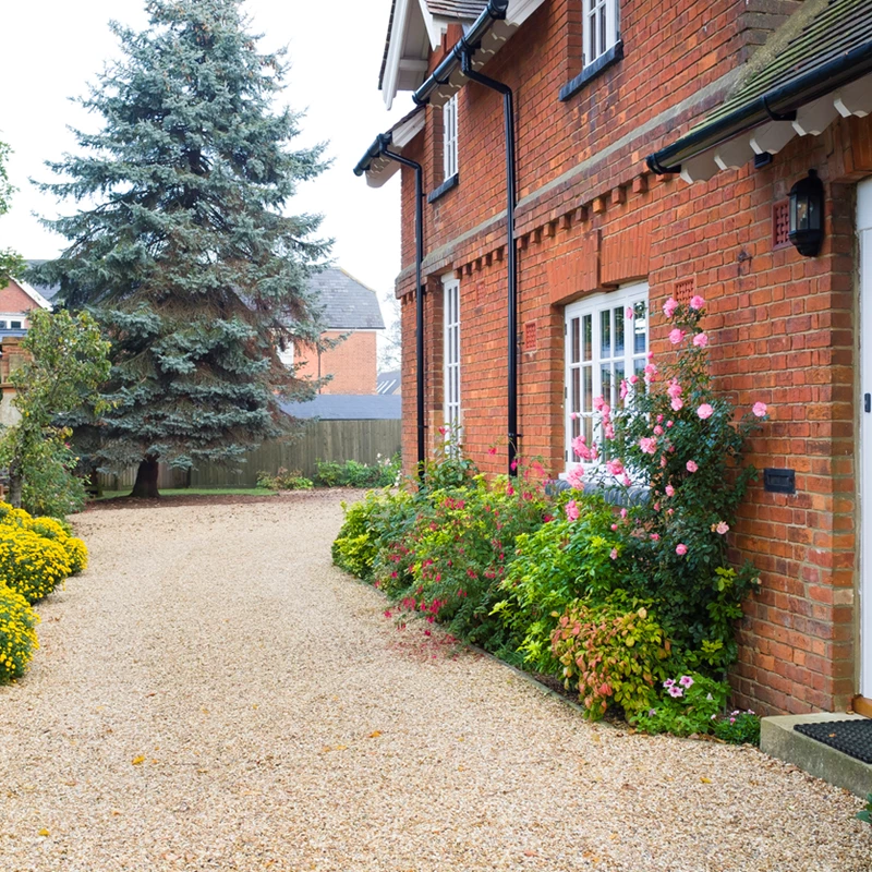 A charming red brick house featuring a front porch and neatly landscaped yard.